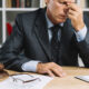 close up exhausted male mature lawyer sitting front desk 80x80